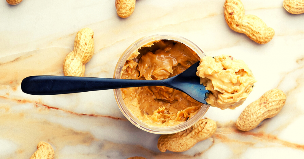 peanut butter in a jar scooped with a spoon
