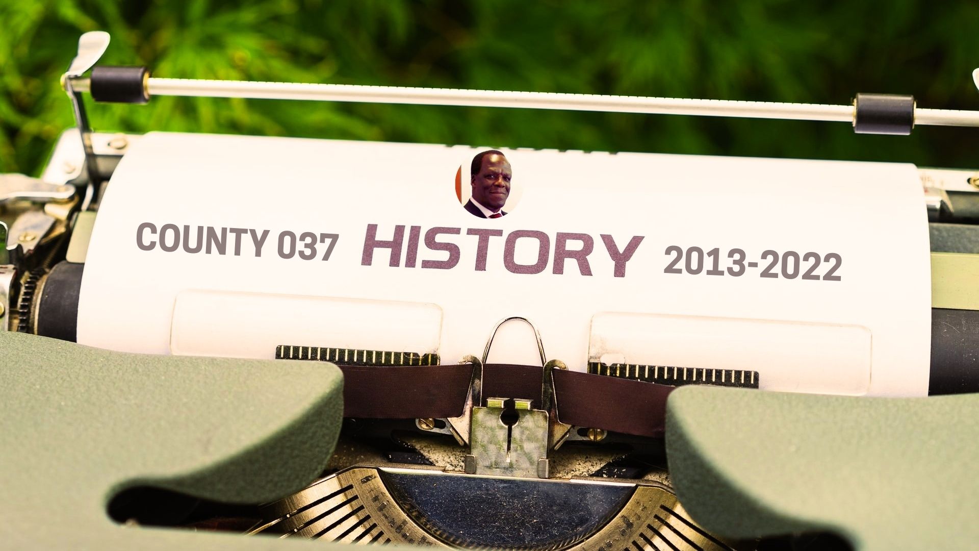 typewriter with image of Kakamega governor oparanya with the heading 'county 037 history 2013-2022'