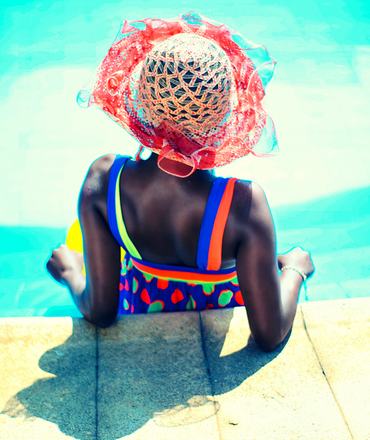 sunny day a woman in a swimming suit and sun hat relaxing by the pool