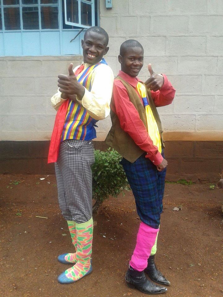 Luhya comedy double act Mtumishi and Mchungaji in costume flashing thumbs up sign