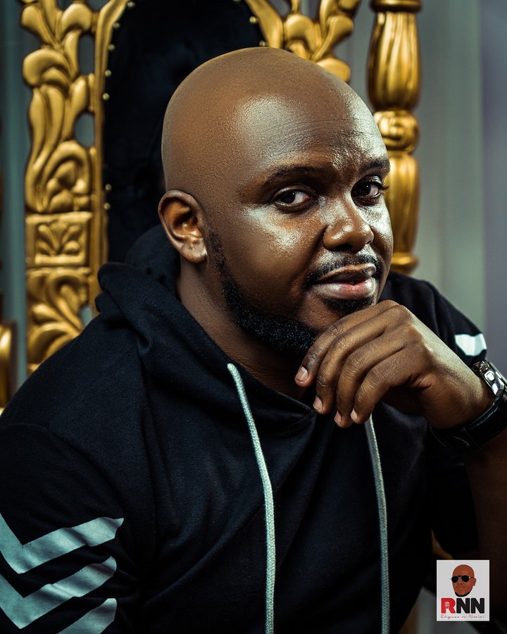 Hubert Nakitare aka Nonini Mgenge  sitting on a throne, his face wearing a smile and holding his chin 