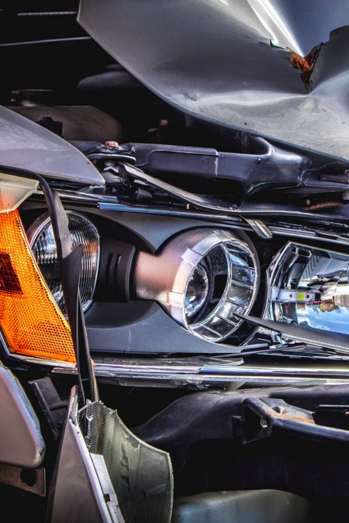 silver grey car that has suffered accident damage involving front lights on one side