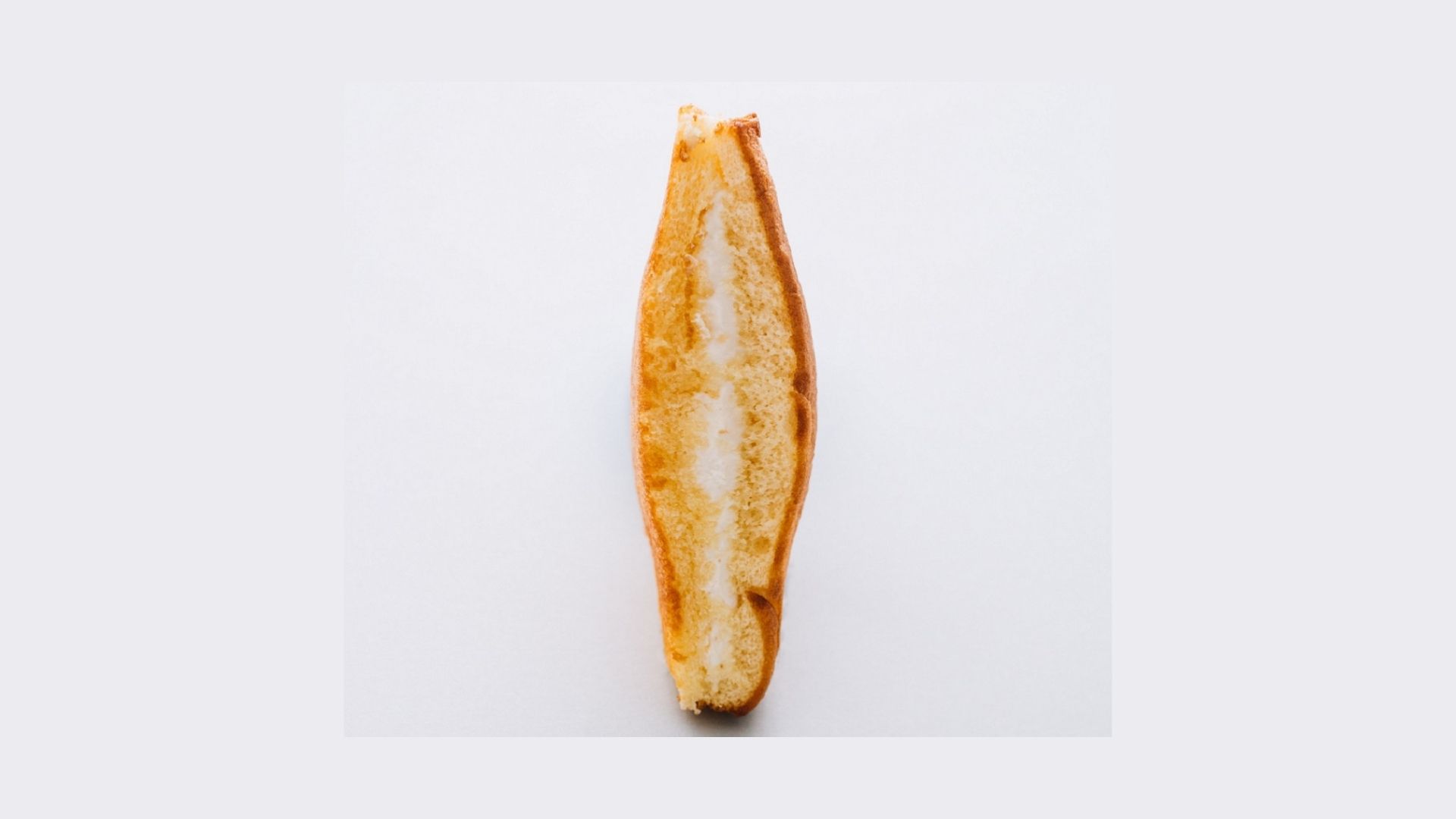 a bread sandwich with cream upon a grey background