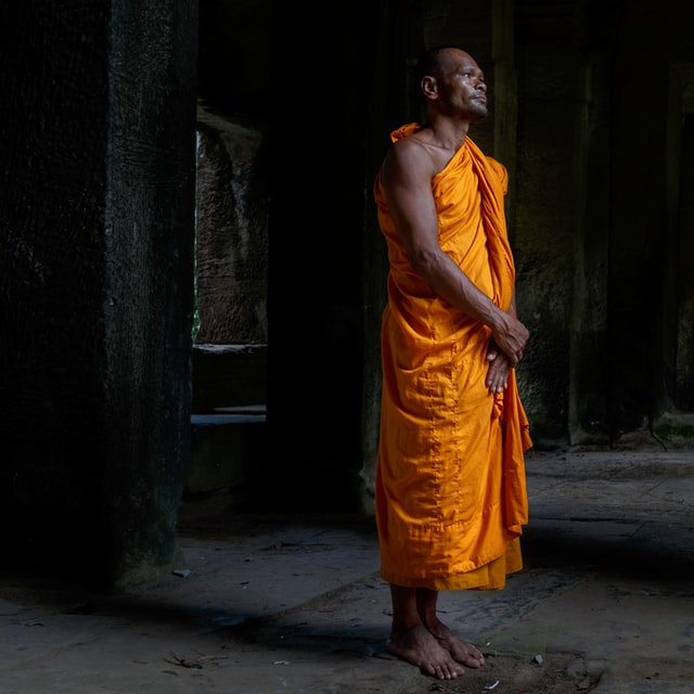 a man in a orange robe stands at attention